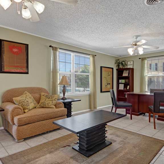 The interior of the front office at Avalon Springs with a desk, bookshelves, chairs, a coffee table, and a couch. 