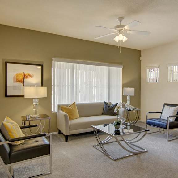 A living room at Dobson Towne Centre with a couch, coffee table, chairs, artwork, and lamps. 