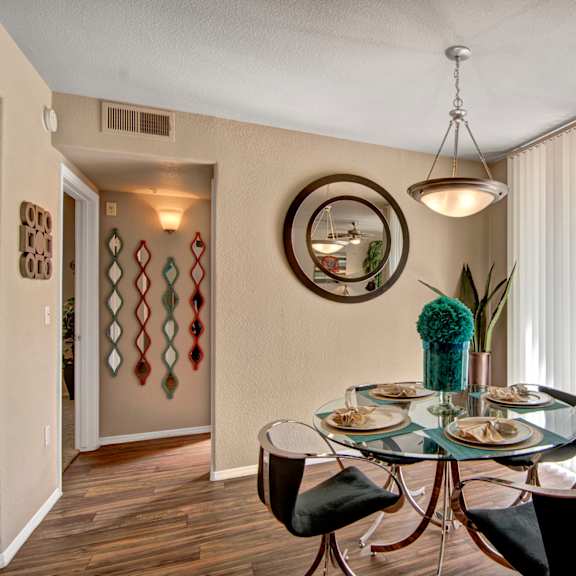 A dining room with a glass table and chairs and sliding glass doors that lead to a balcony or a patio at Hawthorne Apartments. 
