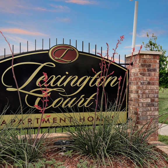 The exterior sign and greenery of Lexington Court Apartment Homes. 