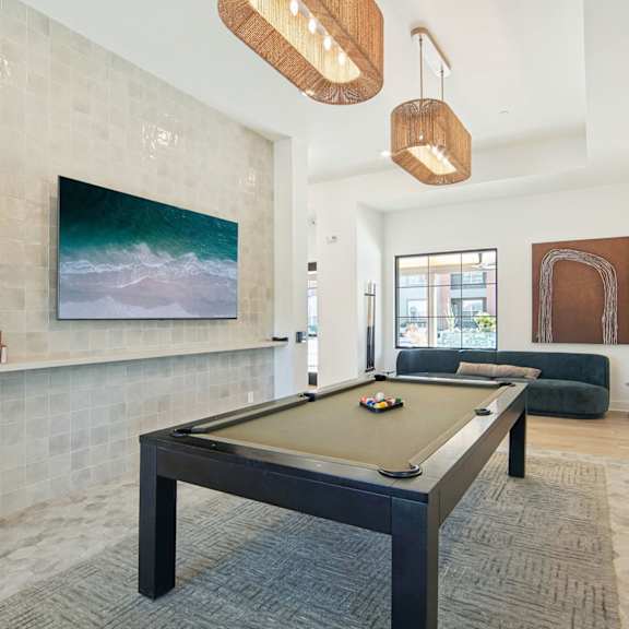 a pool table in a living room with a painting on the wall at The Maddox Luxury Apartment Homes, Buckeye, AZ 85326