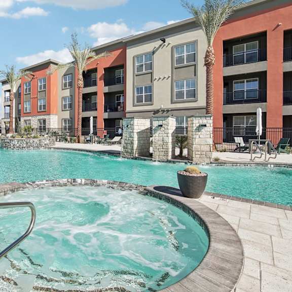 our apartments have a large swimming pool with an umbrella at The Maddox Luxury Apartment Homes, Buckeye, AZ 85326