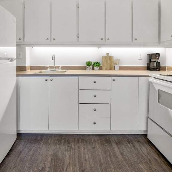 A kitchen with white cabinets and a white refrigerator.
