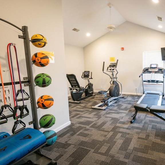 A gym with a variety of equipment including a treadmill, weights, and resistance bands.