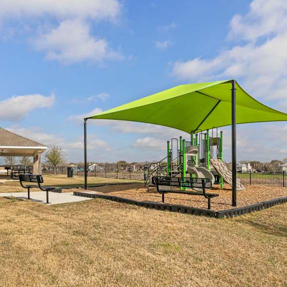 A playground with a green canopy and a slide.
