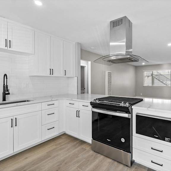 a white kitchen with white cabinets and a stove and oven