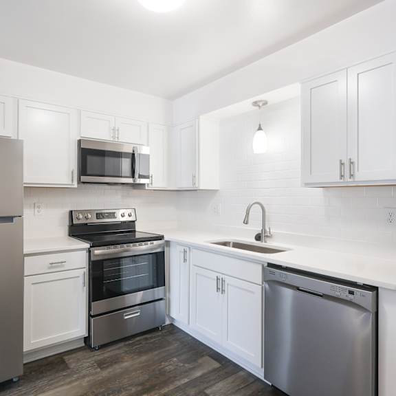 A kitchen with white cabinets and a blue vase on the counter.