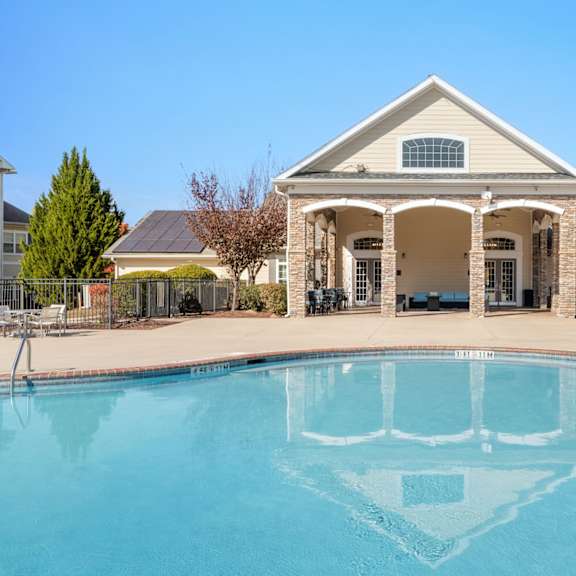 A brick building with a balcony and a tree in front. at Stone Gate Apartments, Spring Lake, 28390
