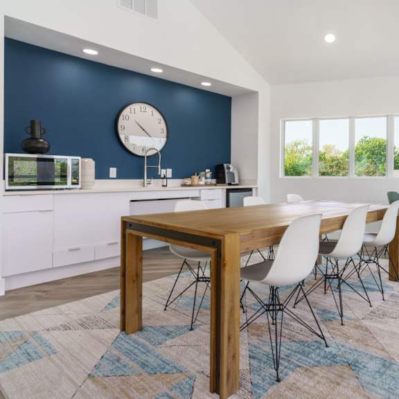 a dining room with a table and chairs and a clock on the wall
