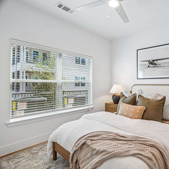 A bedroom with a bed, nightstand, and a picture of a plane on the wall.