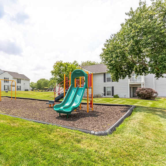 A playground with a green slide and a yellow swing set.