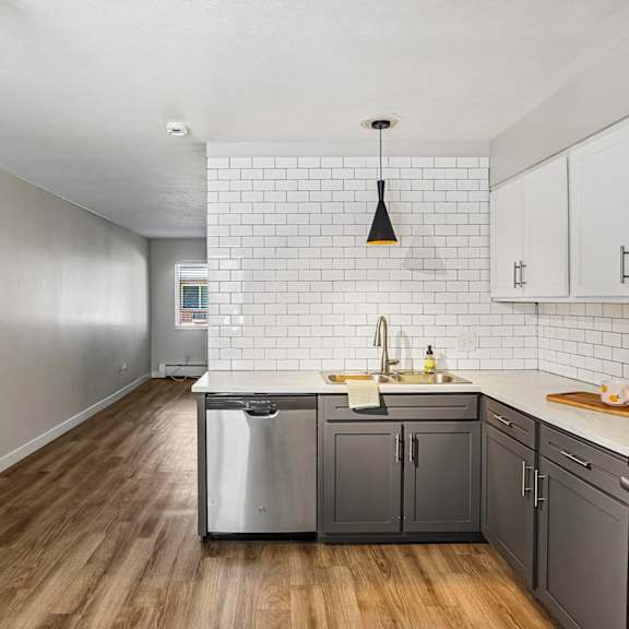 A kitchen with a white tile backsplash and wooden floors.