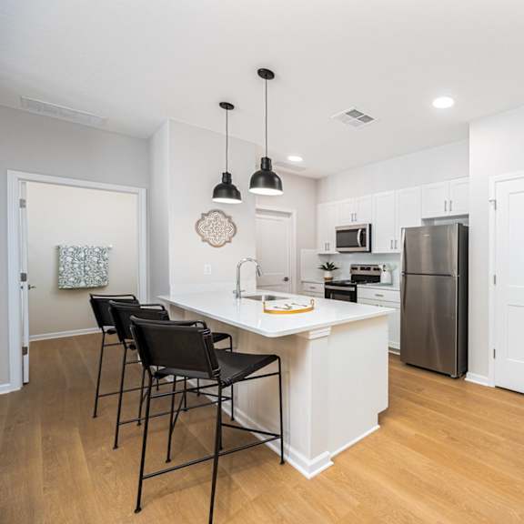 A kitchen with white cabinets and a white island with a counter top.