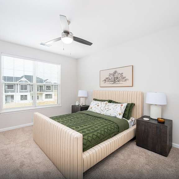 A bedroom with a large bed and a ceiling fan.
