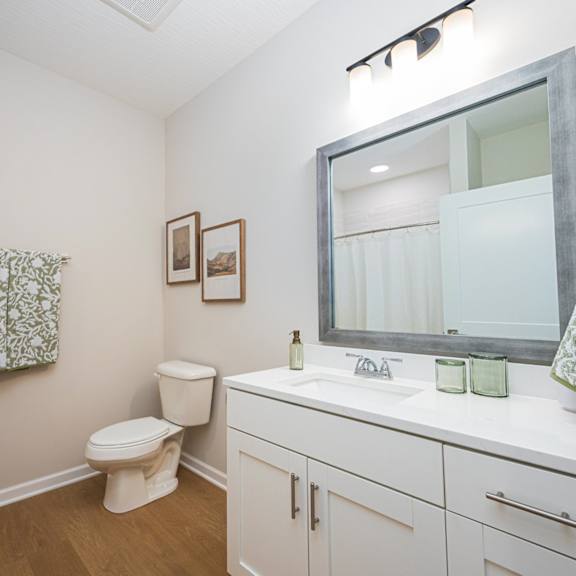 A white bathroom with a toilet, sink, and mirror.