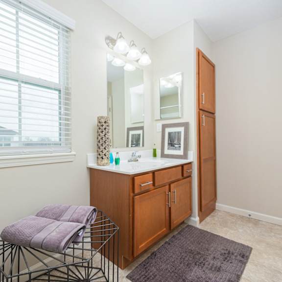A bathroom with a vanity, mirror, and towel rack.