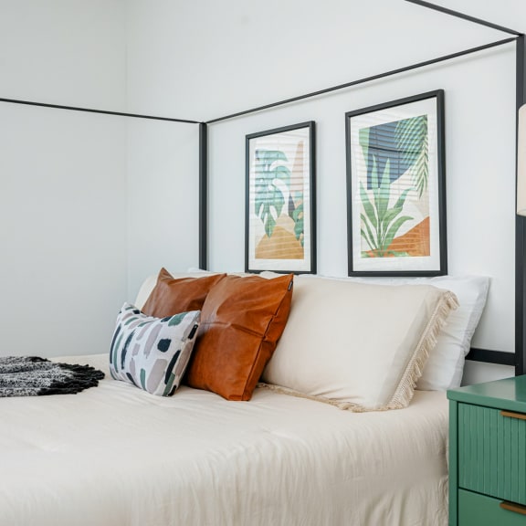 a bedroom with a bed and a lamp and pictures on the wall