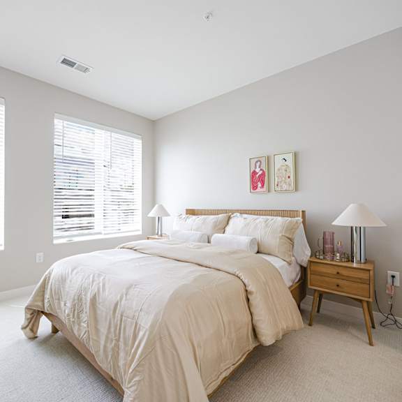 A bedroom with a large bed and a nightstand with a lamp.
