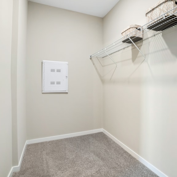 an empty closet with a wire basket hanging on the wall