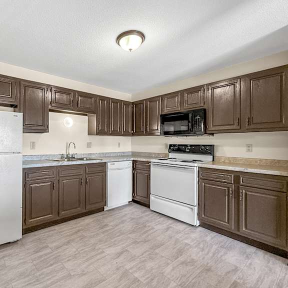 A kitchen with brown cabinets and a white refrigerator.
