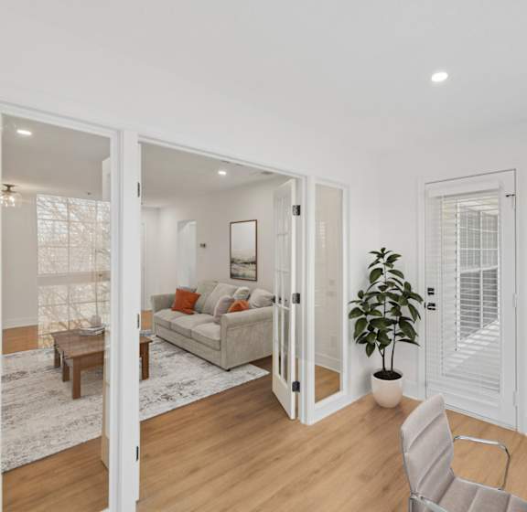 A white room with a couch, a chair, a table, and a potted plant.