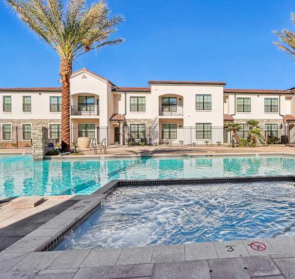 a swimming pool with palm trees and apartments in the background at Stella Luxury Apartment Homes in San Tan Valley, AZ