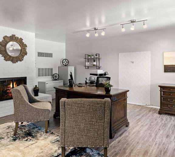 A room with a fireplace, a desk, and chairs.