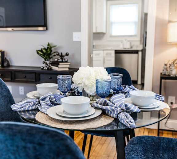 A dining table set with blue chairs and a white flower centerpiece.