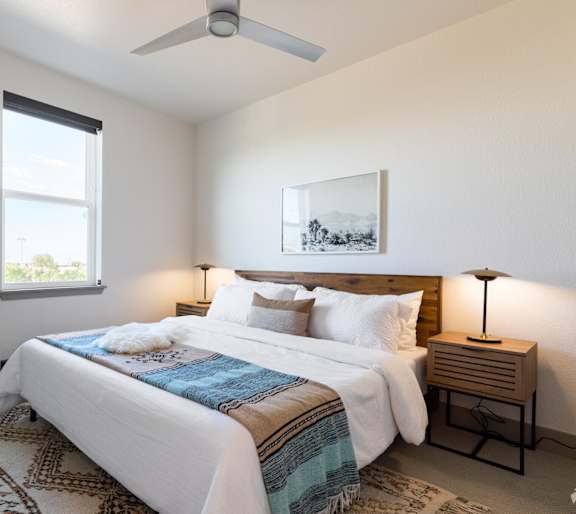 A bedroom with a large bed and a ceiling fan.