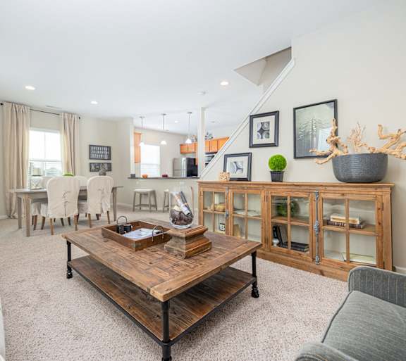 A living room with a couch, coffee table, and staircase.
