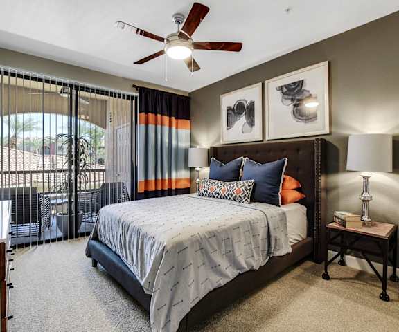 A bedroom with a queen-size bed, closet, and balcony at Desert Club. 
