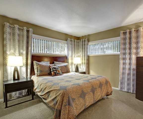 A bedroom with a bed and two windows with curtains at Capitol Towers - Towers and Villas