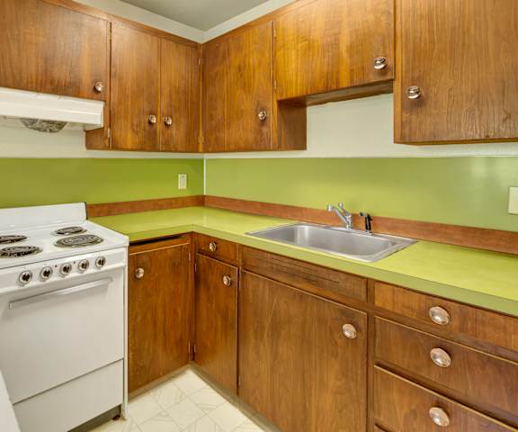 A kitchen with white appliances and green counters at Country Lane Apartments. 