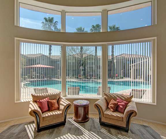 The resident lounge with two chairs overlooking a pool through the windows at Dobson Towne Centre. 
