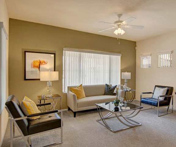 The living room with a couch, coffee table, decorations, a TV, and windows at Dobson Towne Centre. 