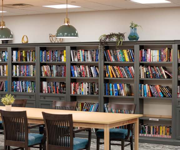 A room with a long table and a bookshelf filled with books.