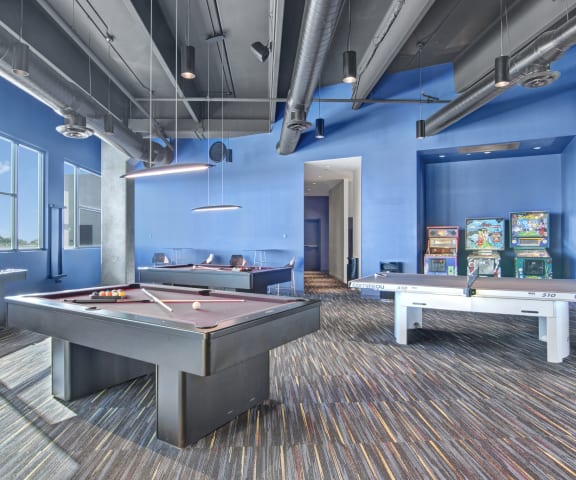 a games room with two pool tables and arcade games