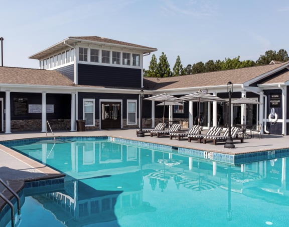 a swimming pool with lounge chairs and umbrellas in front of a building