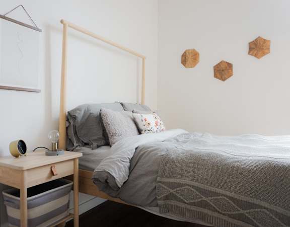 Studio Apartments in Pearl District, Portland, OR - Couch9 - Bedroom with Bed, Wooden Nightstand with Lamp, and Wall Decors.