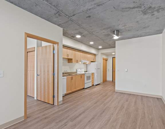 A kitchen area with a white wall and a wooden floor.
