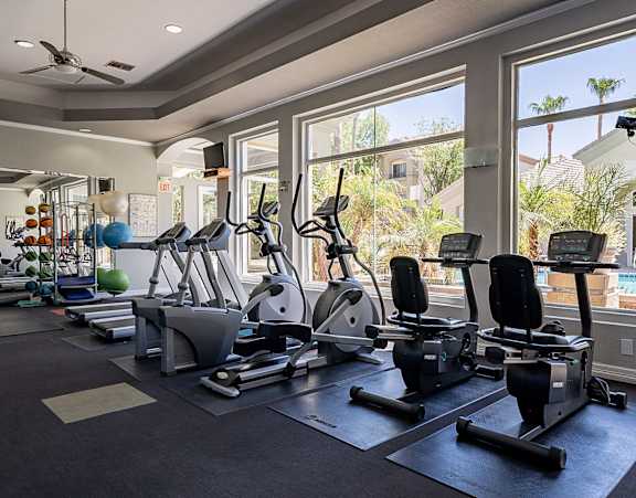 A gym with a row of treadmills and elliptical machines.at Palazzo Townhomes, Phoenix, 85008