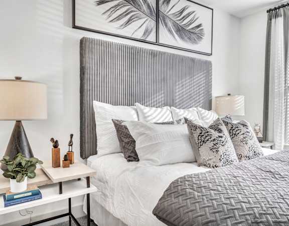 A bedroom with a large bed and a grey headboard.