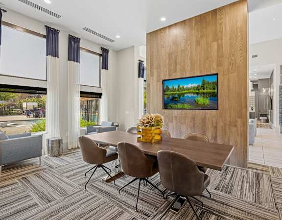 A conference room with a large painting on the wall and a long table with chairs.