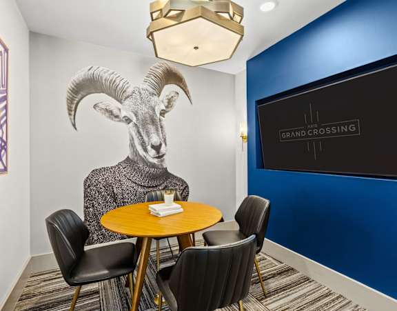 A conference room with a table, chairs, and a painting of a ram on the wall.
