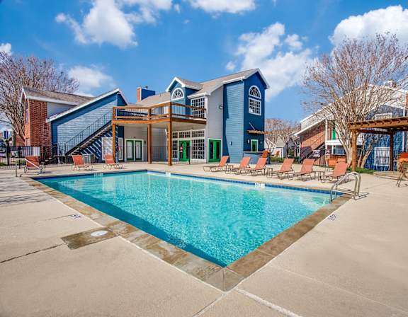 A swimming pool surrounded by chairs and buildings.