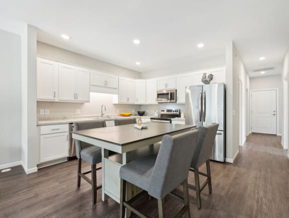 a kitchen with white cabinets and a large island with chairs