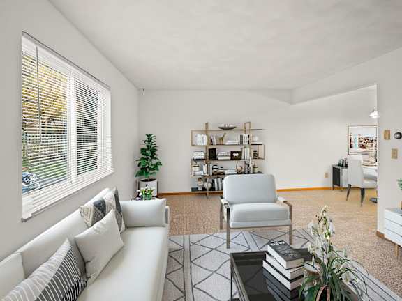 A living room with a white sofa, a chair, a coffee table, and a bookshelf.