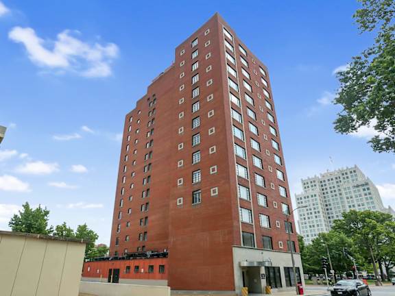 A tall red brick building stands in front of a blue sky.