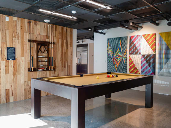 a billiards table in the lobby of a building with a wall of wood
