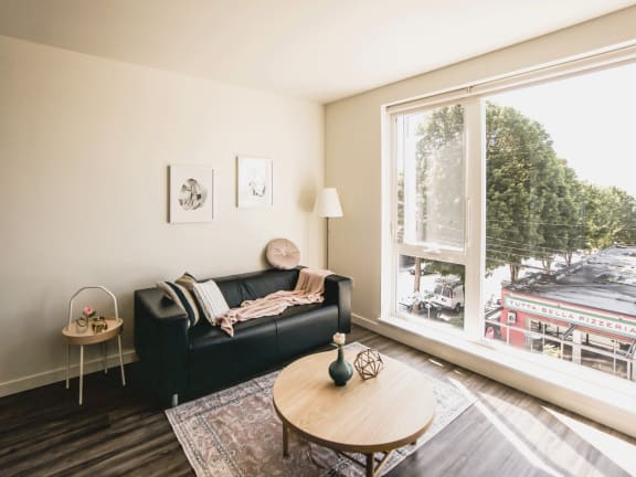 a living room with a large window and a black couch